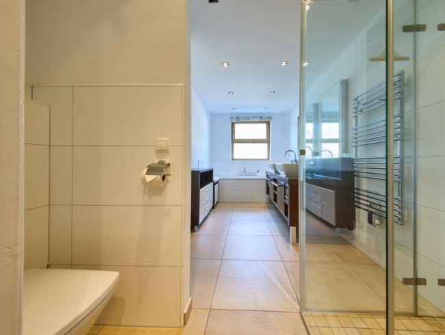 Modernes Badezimmer mit Dusche, Badewanne und Doppelwaschbecken in hellen Farbtönen