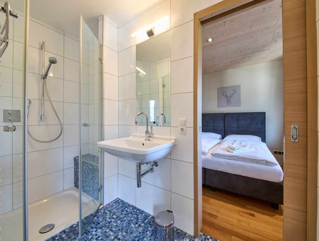 Modernes Badezimmer neben einem gemütlichen Schlafzimmer mit Doppelbett